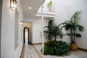 A hallway with a tiled floor, potted plants, and wall-mounted lighting fixtures. - Bright, Well-Equipped Superior Apartment (El Puerto de Santa María)