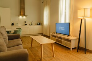 A modern living room with a sofa, a coffee table, a TV on a stand, a lamp, and a kitchen area in the background. - Bright, Well-Equipped Superior Apartment (El Puerto de Santa María)