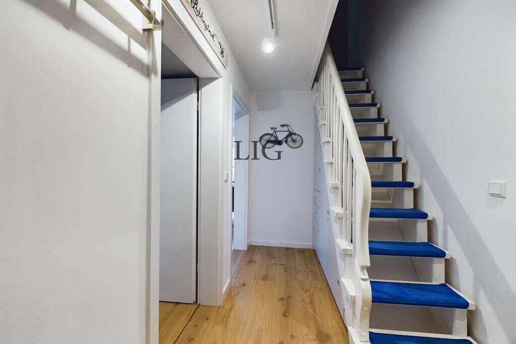 A staircase with blue steps leading to a landing where a bicycle is mounted on the wall.