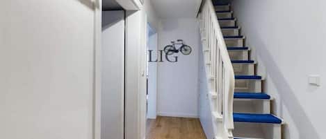 A staircase with blue steps leading to a landing where a bicycle is mounted on the wall.