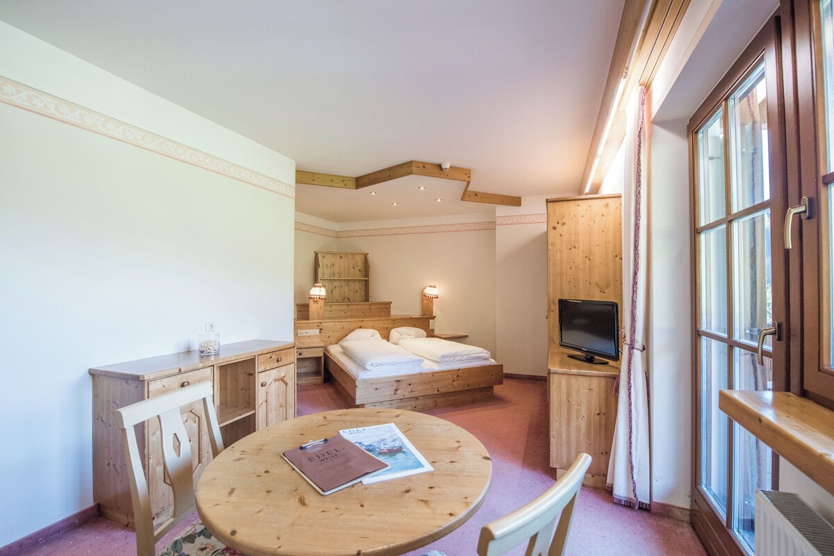 Una habitación con cama, escritorio, silla, mesa y televisor.