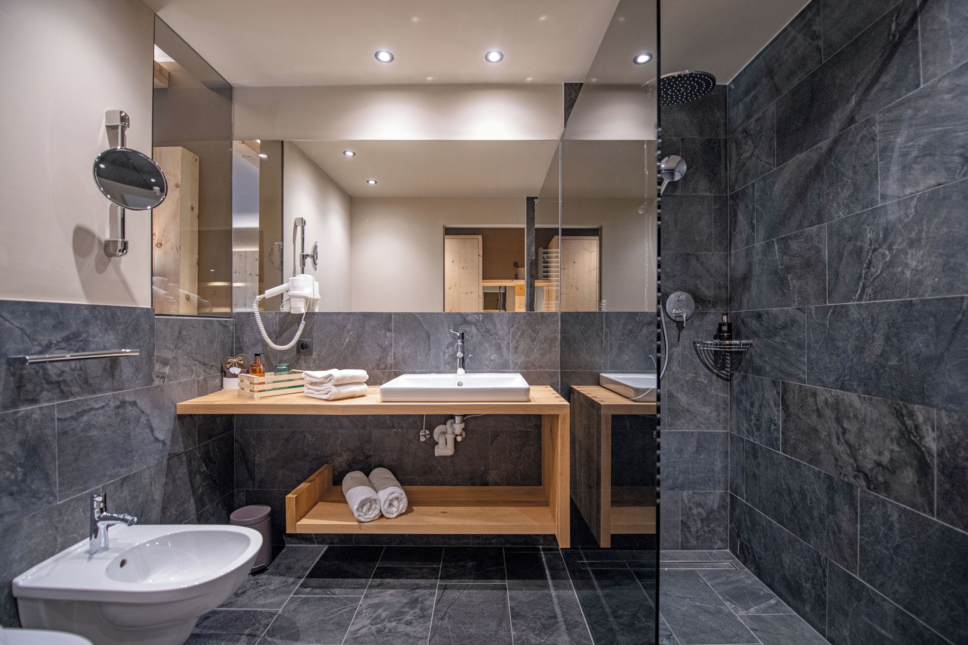 Un baño moderno con un espejo grande, un lavabo, un bidé y una zona de ducha.