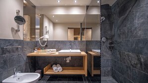 Un baño moderno con un espejo grande, un lavabo, un bidé y una zona de ducha.