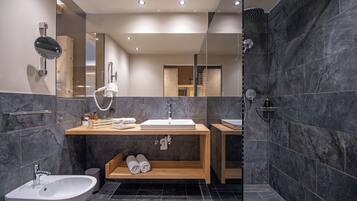 Un baño moderno con un espejo grande, un lavabo, un bidé y una zona de ducha.