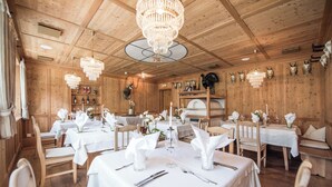 A restaurant with wooden interiors, chandeliers, and tables set for dining.