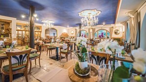 Un restaurante con varias mesas, sillas y un candelabro.