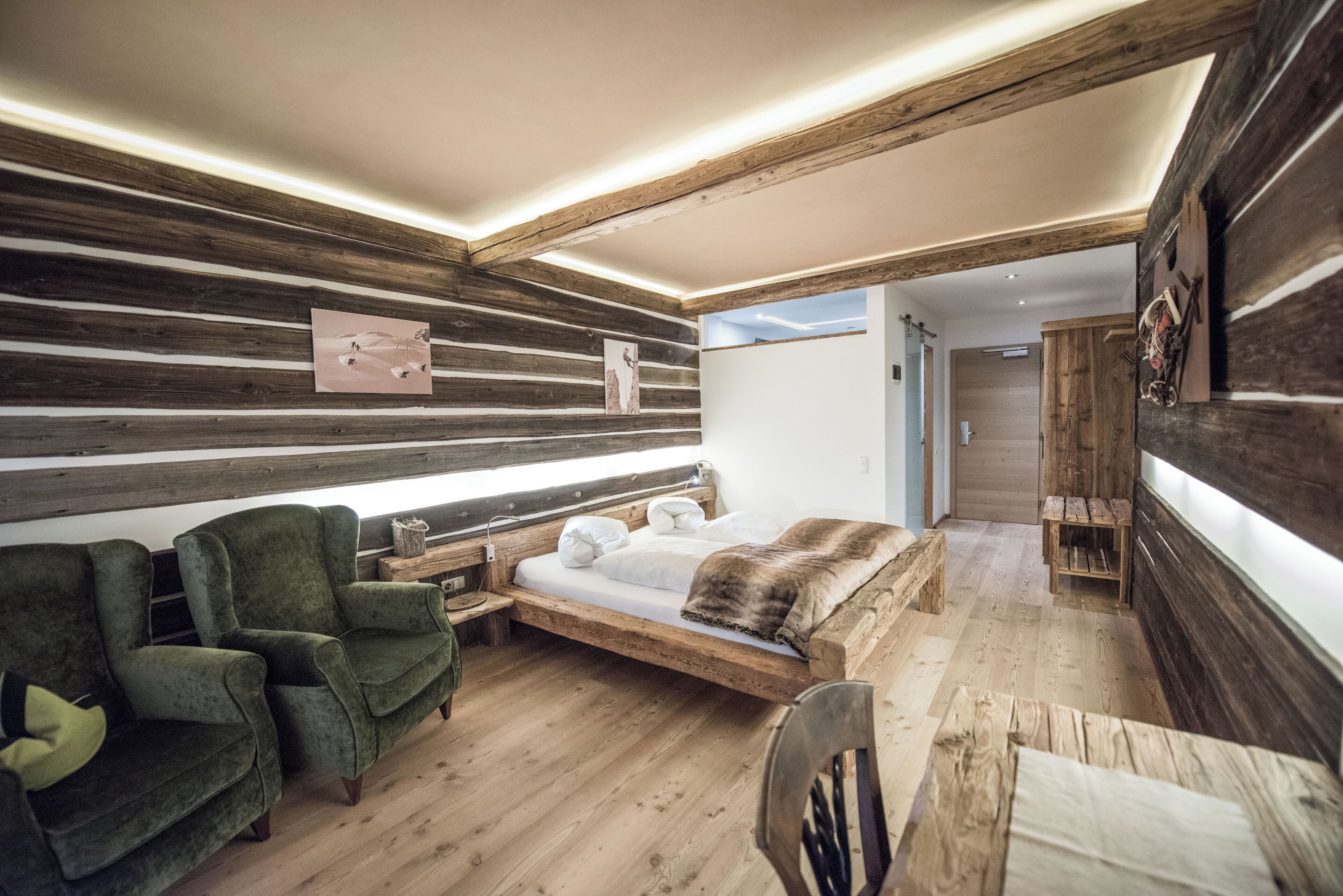 A modern bedroom with a wooden slat wall, a bed with a wooden frame, a green armchair, and a wooden bench.