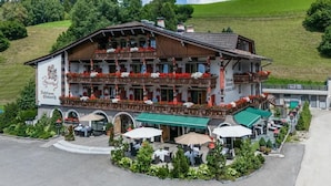 Un edificio tradicional de estilo alpino con un balc ón, mesas al aire libre y un letrero que indica que es un hotel y restaurante.