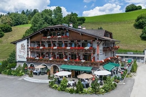 A traditional Alpine-style building with a balcony, outdoor seating, and a sign indicating it is a hotel and restaurant. - Hotel Edel.Weiss (Trentino-Alto Adige)