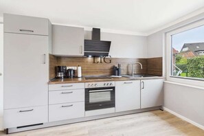 A modern kitchen with a built-in oven, a coffee maker, and a sink. - Erika holiday apartment (Langeoog)