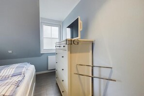 A bedroom with a bed, a dresser, a television on top of the dresser, and a window. - Holiday apartment in Langeoog with Wi-Fi (Langeoog)