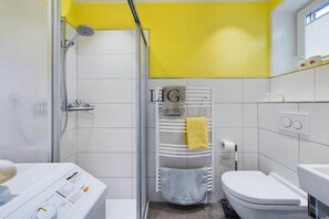 A bathroom with a shower, toilet, and a towel rack with towels. - Holiday apartment in Langeoog with Wi-Fi (Langeoog)