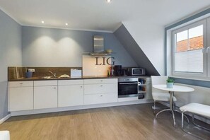A modern kitchen with white cabinets, stainless steel appliances, and a visible 'LIG' sign. - Holiday apartment in Langeoog with Wi-Fi (Langeoog)