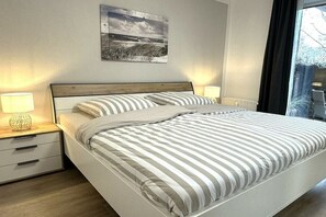 Une chambre à coucher avec un lit, des tables de chevet, une lampe et une fenêtre.