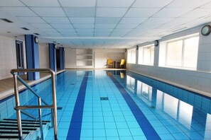 Une piscine avec un sol carrelé et un escalier en métal.