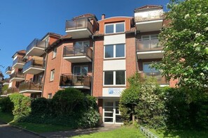 Un immeuble résidentiel à plusieurs étages, doté de balcons, d’une entrée sécurisée et d’une plaque indiquant l’adresse.