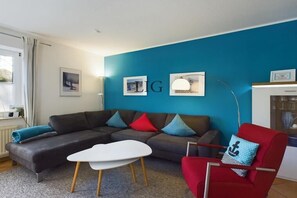 Ein modernes Wohnzimmer mit einem grauen Sofa, einem roten Sessel und einem weißen Couchtisch.