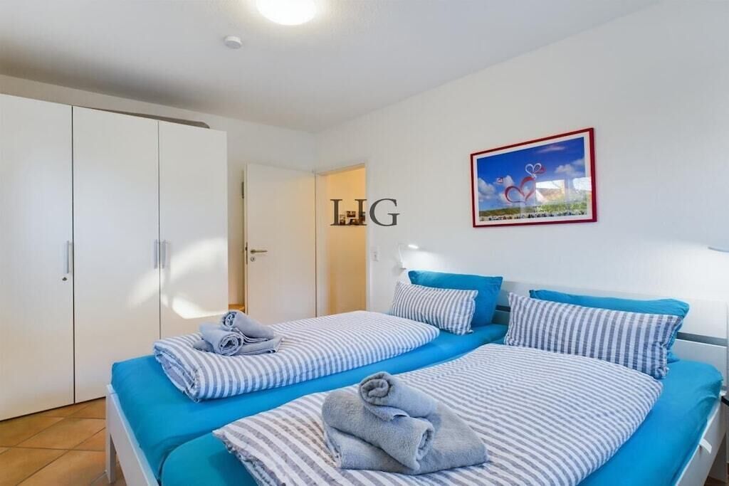 A hotel room with two beds, striped bedding, a framed picture on the wall, and a wardrobe.