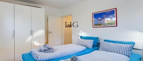 A hotel room with two beds, striped bedding, a framed picture on the wall, and a wardrobe.