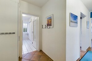 Ein Flur mit gefliestem Boden, einer Tür mit silbernem Griff und einem an der Wand befestigten Schild mit der Aufschrift 'LIG'.
