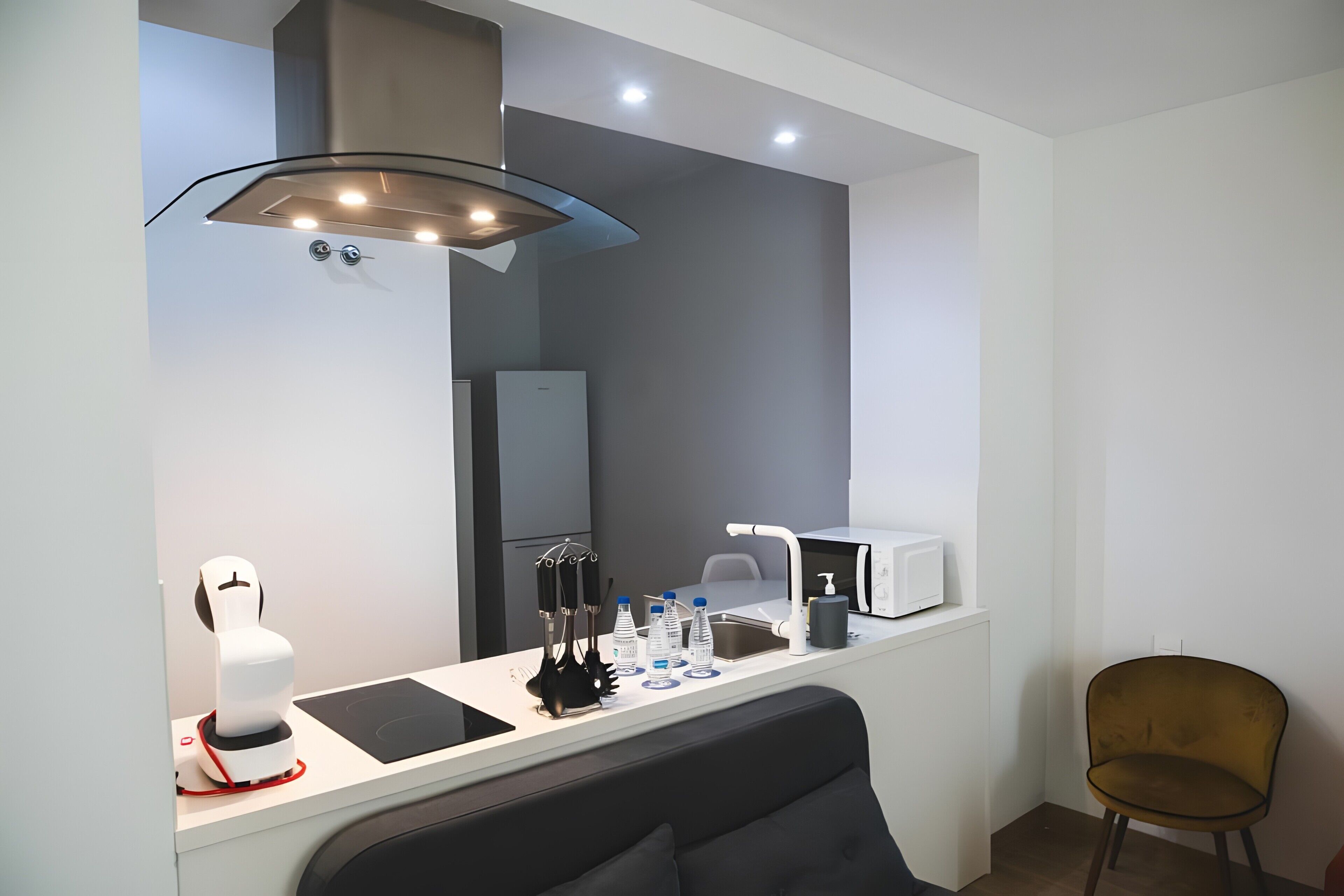 Une chambre moderne équipée d’un bureau, d’une chaise, d’un four à micro-ondes, d’un distributeur d’eau et d’une machine à café.