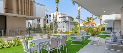 A modern outdoor patio with a dining area, seating, and a view of the surrounding buildings.