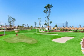 Een golfbaan met een vlag, zandbunkers en een heldere lucht.