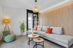 A modern living room with a grey sofa, two round coffee tables, a floor lamp, and a potted plant. - Santa Rosalía Tropical Garden Corner, pool, lagoon, beach bar, gym by OYOOSTAYS (Torre-Pacheco)