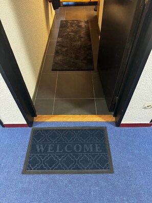A hotel entrance with a dark rug, a welcome mat, and a blue carpet. - La Vue Blanche – Spacious, Balcony & Mont Blanc View (Chamonix)