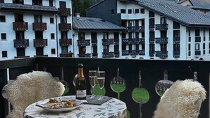 Uma área de refeições com uma mesa posta para dois, com vista para uma paisagem montanhosa.