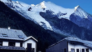Uma montanha com picos cobertos de neve e uma aldeia com edifícios tradicionais.
