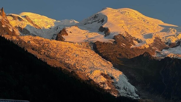 Paisagem de montanha com picos cobertos de neve e um vale.