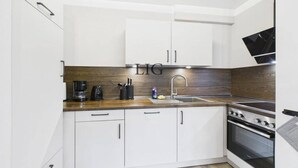 Een moderne keuken met witte kastjes, een houten aanrecht, een roestvrijstalen spoelbak en een inbouwoven.