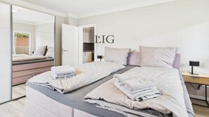 Een moderne slaapkamer met een groot bed, een nachtkastje en een spiegel.