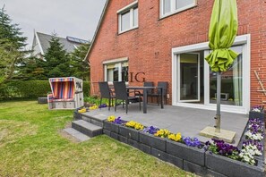 A brick house with a patio area, outdoor seating, and a mailbox. - Holiday apartment Strandkoje (Langeoog)