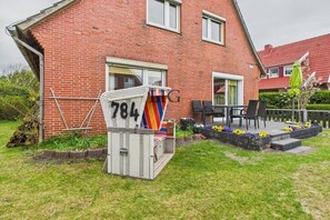 A brick house with a small garden, a white outdoor seating area, and a mailbox with the number 704. - Holiday apartment Strandkoje (Langeoog)