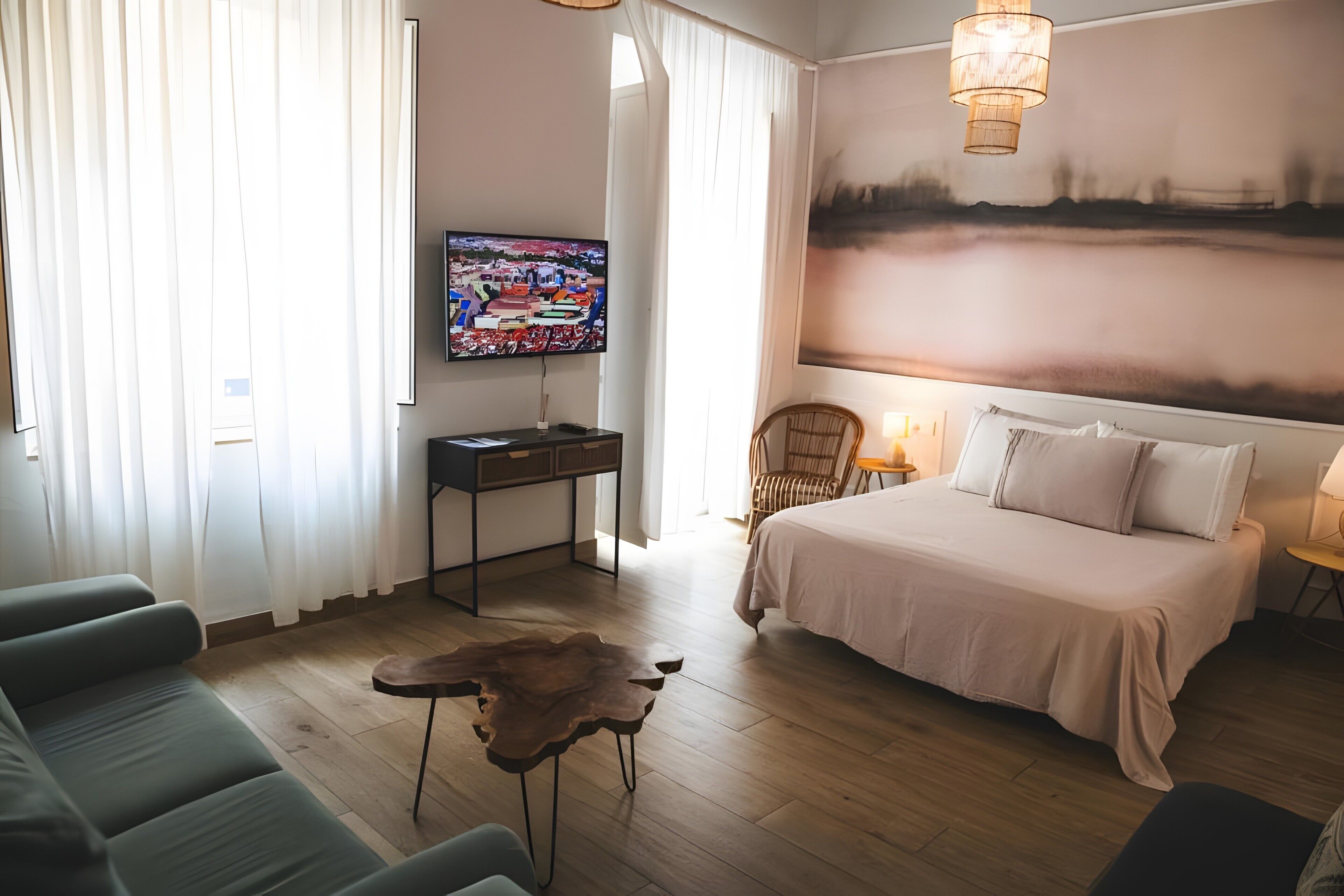 A hotel room with a bed, a TV, a desk, a chair, and a wooden coffee table.