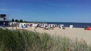 A beach with rows of beach chairs and umbrellas, a pier in the background, and a clear sky. - Holiday apartment with 2 bedrooms (Ueckermünde)