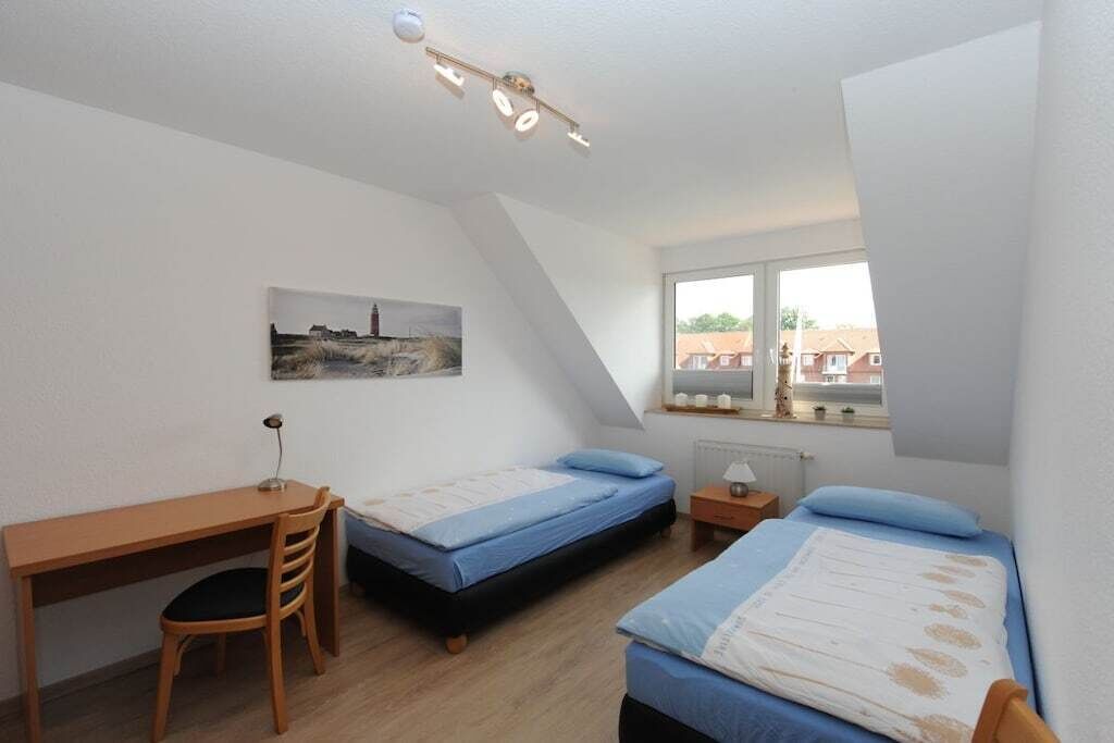 A bedroom with two single beds, a desk, and a chair.