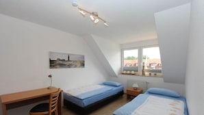 A bedroom with two single beds, a desk, and a chair. - Holiday apartment with 2 bedrooms (Ueckermünde)