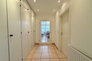 A corridor with lockers, a radiator, and a door with a window. - Holiday home with 1 bedroom (Travemünde)