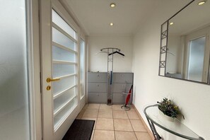 A hotel room with a sliding door, a small wardrobe, a mirror, and a glass table with a plant. - Holiday home with 1 bedroom (Travemünde)