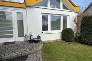 A house with a white exterior, a garage door, and a paved driveway. - Holiday home with 1 bedroom (Travemünde)