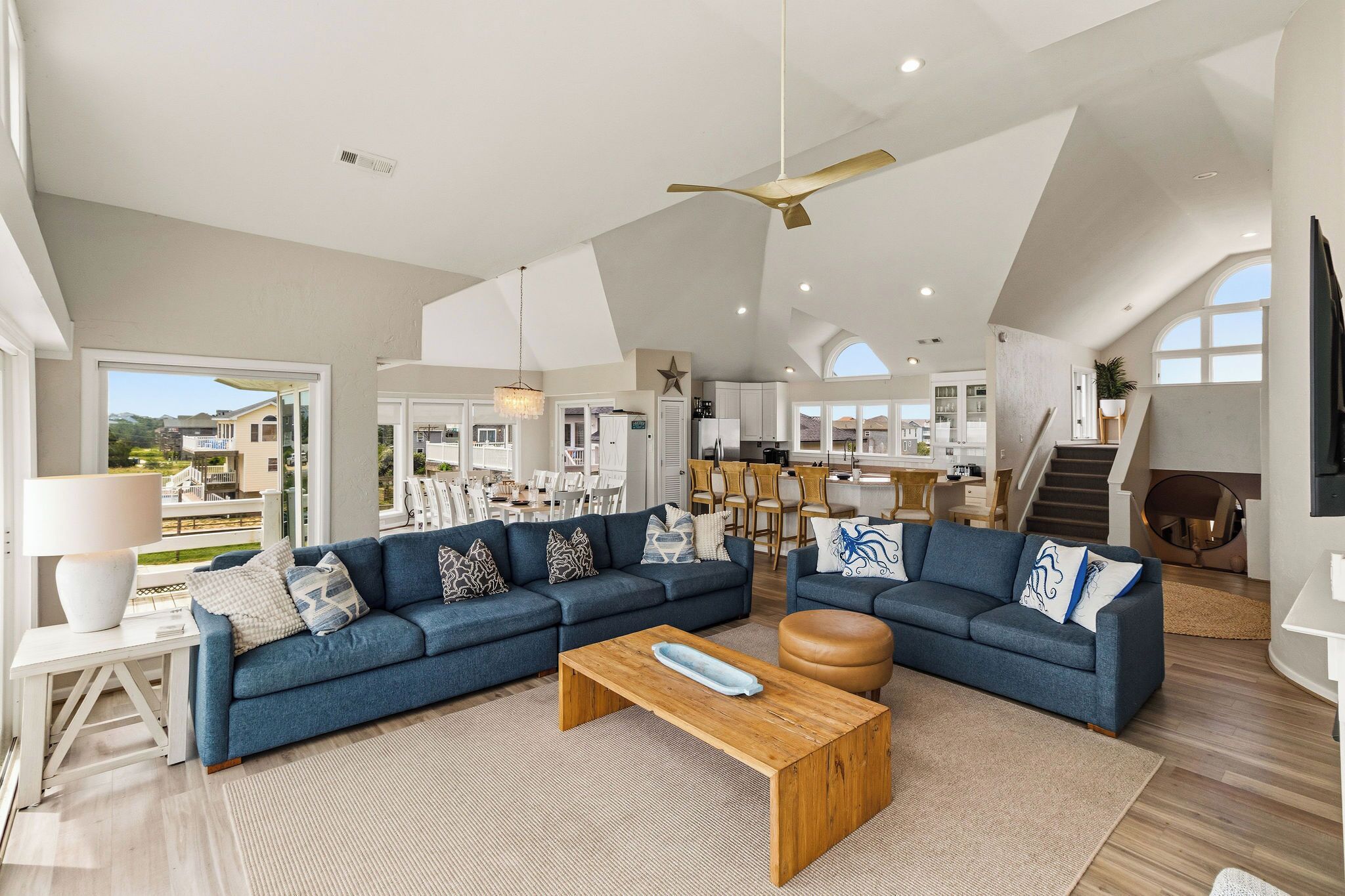A spacious living room with a sectional sofa, a wooden coffee table, and a view of the kitchen and dining area.
