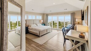 Una camera da letto con un letto, una scrivania e una sedia, con vista sul mare.