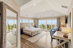 A bedroom with a bed, a desk, and a chair, with a view of the sea. - Elevator, Theater Room, Game Room, Duck, Oceanfront, Pool, D0128 (Duck)