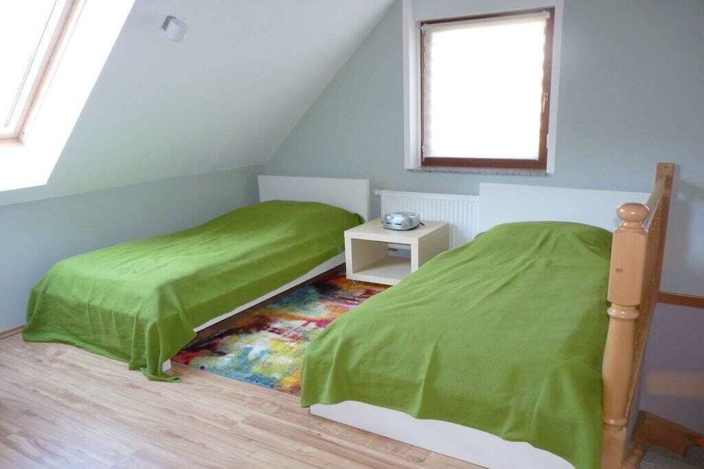 A small, single-room with two single beds, a radiator, and a window.