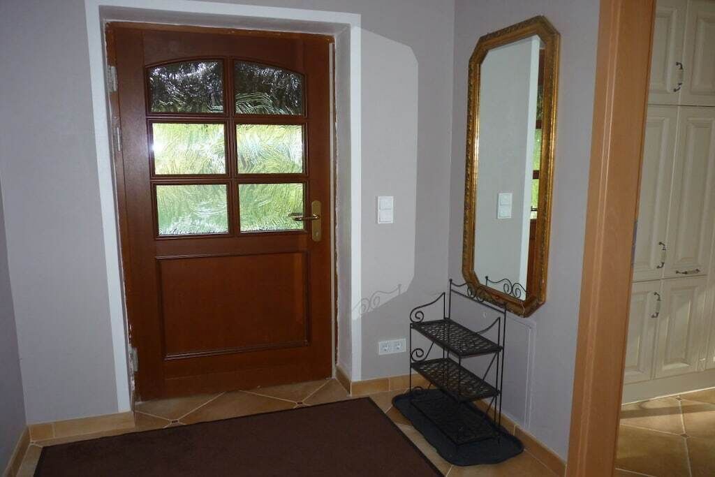 Une porte en bois avec un panneau de verre, une étagère en métal et un miroir accroché au mur.