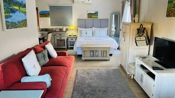 Una habitación de hotel con una cama, un sofá rojo, una televisión y un escritorio.