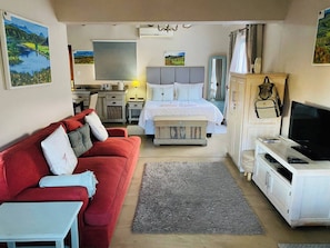 Een hotelkamer met een bed, een rode bank, een televisie en een bureau.
